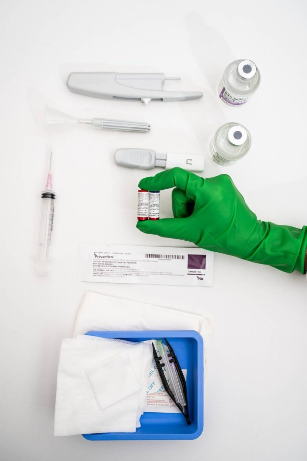 Hormone pellets held up beside a prepared treatment tray